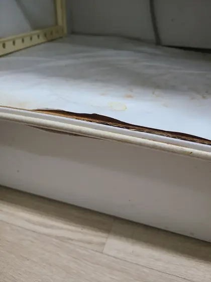 싱크대 하부장 물고임 — 앞쪽 가장자리가 검게 갈라진 바닥판