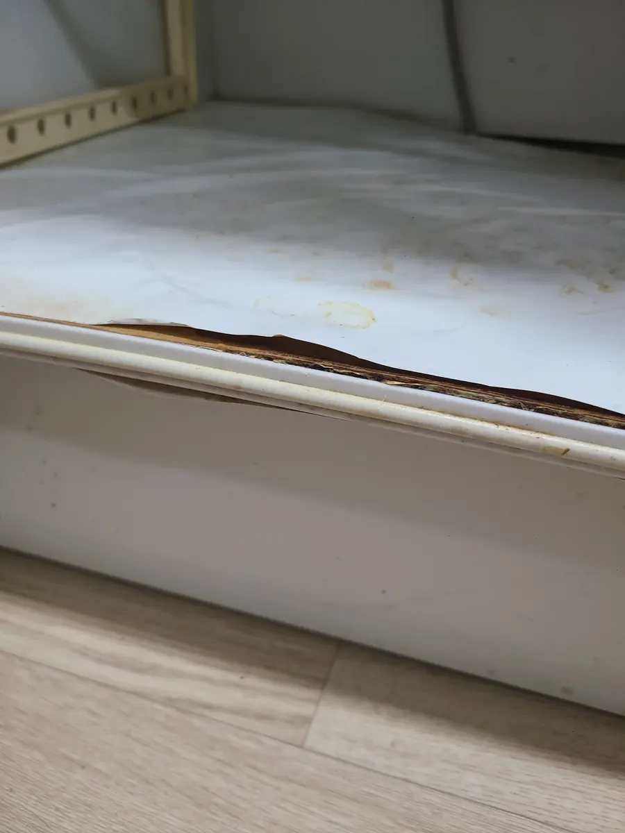 싱크대 하부장 물고임 — 앞쪽 가장자리가 검게 갈라진 바닥판